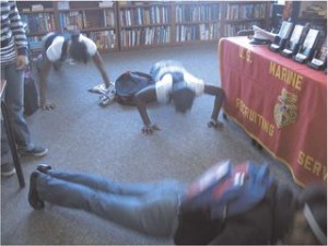 Note. Photo by K. Barker. FIGURE 1—Students at Garfield High School in Seattle, WA, drop to the floor for pushups under the command of a military recruiter at the school in 2009.
