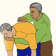 Two men, one man is helping to loosen congestion of another man by rubbing his back with his the heel of his hand.