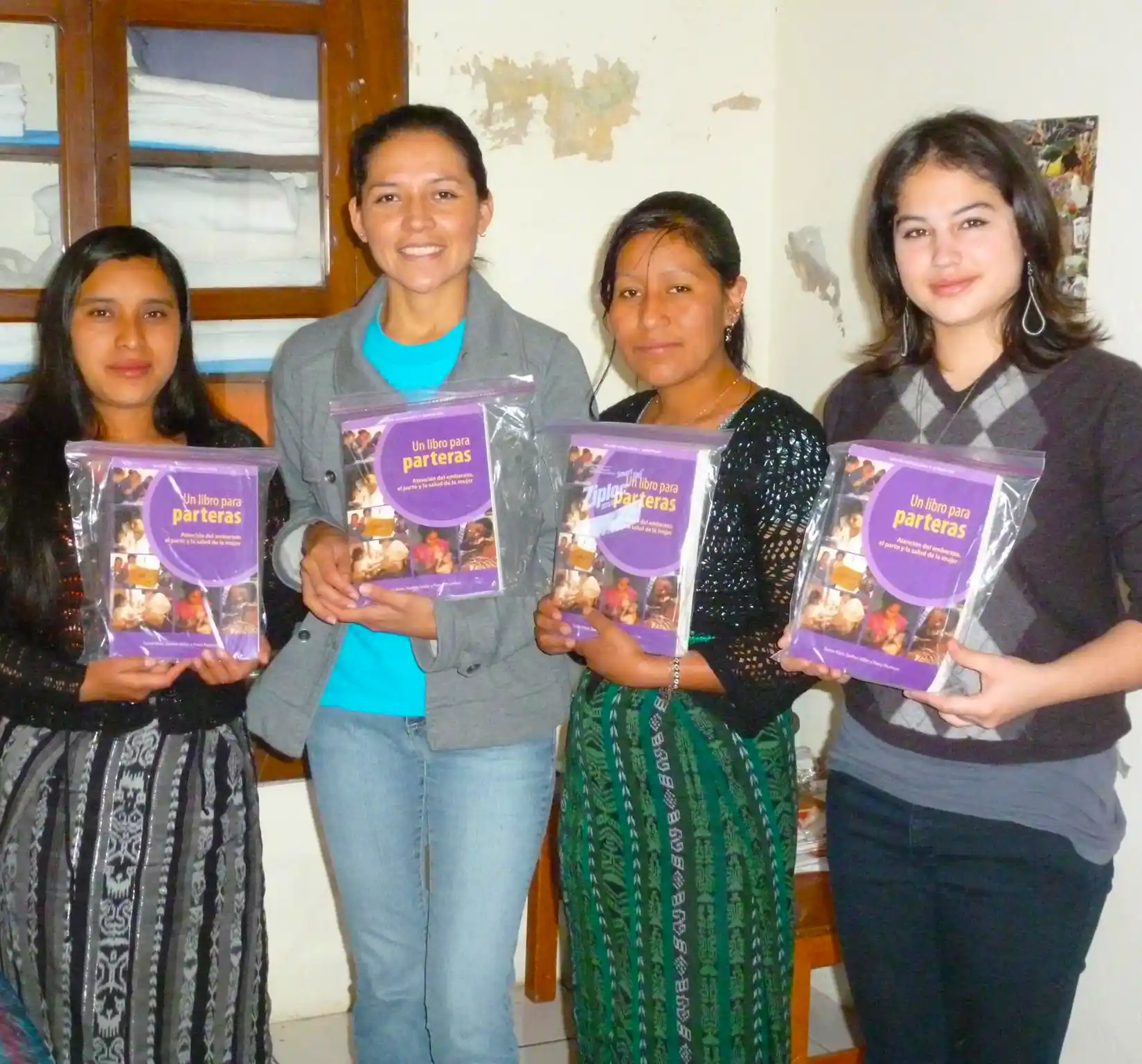 A group of women training to be midwives in Guatemala hold up their gratis copies of A Book for Midwives for the camera.